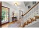 Charming foyer with hardwood floors, wooden staircase, and natural light from the open door at 102 Pin Oak Ct, Elon, NC 27244