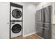 Laundry room with stainless steel refrigerator and stacked washer dryer to maximize the utility of this condo at 1061 Wirewood Dr # 303, Raleigh, NC 27605