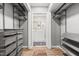 View of walk-in closet featuring custom shelving and a view into the ensuite bathroom with ornate rug and hardwood floors at 1061 Wirewood Dr # 303, Raleigh, NC 27605