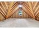Spacious unfinished attic showcasing exposed wood beams and a small window, offering potential for customization at 1128 Neuse Ridge Dr, Clayton, NC 27527