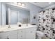 Well-lit bathroom with a double sink vanity, tile floors, framed mirror, and a patterned shower curtain at 1128 Neuse Ridge Dr, Clayton, NC 27527