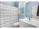 Bright bathroom featuring a white sink, mirror, toilet, and a shower/tub combo with a striped curtain at 1128 Neuse Ridge Dr, Clayton, NC 27527