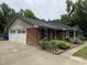 A brick house featuring an attached two-car garage, complemented by lush greenery and mature cacti at 1208 Hatch Rd, Chapel Hill, NC 27516