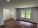 An open-concept living room with new paint, wood-look flooring, and a large window at 1208 Hatch Rd, Chapel Hill, NC 27516