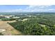 Wide aerial shot showing the land's diverse landscape, revealing agricultural fields and lush wooded areas under a bright sky at 1401 Berea Rd, Rougemont, NC 27572