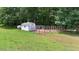 A white storage shed with a fenced-in animal pen adjacent to a lush green field and mature trees at 1401 Berea Rd, Rougemont, NC 27572
