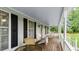 Spacious porch features wood flooring and white railings with seating and wooded views at 1401 Berea Rd, Rougemont, NC 27572