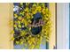 Close-up of a yellow front door adorned with a vibrant floral wreath, creating a cheerful entrance at 1448 Big Falls Dr, Wendell, NC 27591