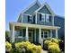 Charming two-story home with a welcoming front porch, yellow door, and manicured landscaping at 1448 Big Falls Dr, Wendell, NC 27591