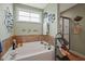 Corner tub with tile, decorative wall art, and a glass-doored shower at 15 Scuppernong Ln, Lillington, NC 27546