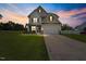 Inviting two-story home featuring a manicured lawn and a charming two-car garage, displayed under a captivating twilight sky at 15 Scuppernong Ln, Lillington, NC 27546
