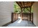 View of a shaded back patio with a privacy fence and the underside of a deck above at 1527 Haywards Heath Ln, Apex, NC 27502