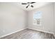 Well-lit bedroom with a ceiling fan and light gray plank flooring and window with view of a second home at 1527 Haywards Heath Ln, Apex, NC 27502