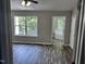 Bedroom with hardwood floors, neutral paint, and ensuite bathroom with large window at 1527 Haywards Heath Ln, Apex, NC 27502