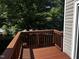 A wood deck with wood railing overlooks a yard full of mature shade trees at 1527 Haywards Heath Ln, Apex, NC 27502