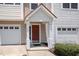 Exterior view of a townhome entrance with a garage, a brick-red door, and a decorative porch roof at 1527 Haywards Heath Ln, Apex, NC 27502