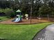 Community playground with play structures and swings, surrounded by green grass and trees at 1527 Haywards Heath Ln, Apex, NC 27502