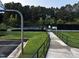 Outdoor tennis court with manicured landscaping and a pathway to the entrance at 1527 Haywards Heath Ln, Apex, NC 27502