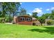 Brick home featuring a well-maintained lawn, mature trees, and a cozy wooden back deck at 202 Crest Rd, Cary, NC 27513