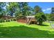 Beautiful brick home boasts a green lawn, mature trees, and an inviting wooden back deck at 202 Crest Rd, Cary, NC 27513