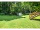 Expansive backyard with lush lawn, mature trees, steps to the house, and a storage shed at 202 Crest Rd, Cary, NC 27513