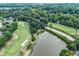 A scenic aerial view showcases the lush green golf course, pond, and verdant trees of the surrounding landscape at 2205 Landings Way, Raleigh, NC 27615
