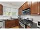 Modern kitchen with wood cabinets, stainless steel appliances, dark countertops, and a window providing natural light at 222 Ashton Hall Ln, Raleigh, NC 27609
