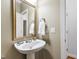 Cozy powder room with pedestal sink, decorative mirror, and neutral wall color at 222 Ashton Hall Ln, Raleigh, NC 27609