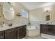 Bathroom with dual sinks, soaking tub with tile backsplash, and dark wood cabinets at 347 Country Mill Way, Fuquay Varina, NC 27526