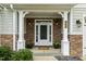 Inviting front porch with stone accents, white columns, decorative lighting, and meticulously maintained landscaping at 347 Country Mill Way, Fuquay Varina, NC 27526