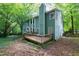 Green two-story home featuring a wood deck, swing set, and mature trees in a leafy backyard at 3511 Shady Creek Dr, Durham, NC 27713