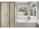 Bright bathroom featuring a soaking tub with jets next to a glass-enclosed shower and window view at 3511 Shady Creek Dr, Durham, NC 27713