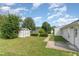 Well-maintained backyard featuring green grass, shrubbery, shed, and a concrete patio at 5437 Advantis Dr, Raleigh, NC 27610