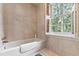 Cozy bathroom with a bathtub, a large window, and cream-colored tile at 820 Kenmore Rd, Chapel Hill, NC 27514