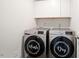 Modern laundry room featuring front-load washer and dryer with decorative covers and storage cabinets at 10 Forest Brook Way, Clayton, NC 27520