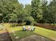 Lush backyard features fire pit, play set, and plenty of room for outdoor activities surrounded by trees at 1003 Burnt Hickory Ct, Apex, NC 27502