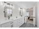 Beautiful bathroom featuring double sinks, white cabinets, black hardware, and decorative tile flooring at 107 Trackimire Ln, Apex, NC 27539