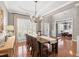 Open-concept dining room featuring hardwood floors, an elegant chandelier, and shuttered windows at 107 Trackimire Ln, Apex, NC 27539