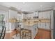 Bright kitchen featuring white cabinets, an island with barstool seating, and stainless steel appliances at 107 Trackimire Ln, Apex, NC 27539