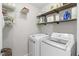 Efficient laundry room equipped with modern white appliances, open shelving, and ample storage space at 107 Trackimire Ln, Apex, NC 27539