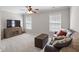 Living room with neutral walls and carpet, ceiling fan, and a large leather sofa with decorative pillows at 107 Trackimire Ln, Apex, NC 27539