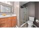Bathroom displaying a stand-up shower with glass doors, toilet, and vanity with wood cabinets at 10941 Pendragon Pl, Raleigh, NC 27614