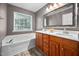 Bathroom showcasing a tub, dual sink vanity with white countertop, wood cabinets, and decorative mirror at 10941 Pendragon Pl, Raleigh, NC 27614