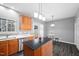 Well lit kitchen with wood cabinets, stainless steel dishwasher, kitchen island, and gray walls at 10941 Pendragon Pl, Raleigh, NC 27614