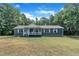 A cozy house with white-trimmed windows and a covered front porch amidst a verdant yard at 1118 Oakridge Duncan Rd, Fuquay Varina, NC 27526