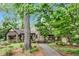 Charming Tudor home featuring a stone tower, surrounded by lush landscaping and mature trees at 1164 Keith Hills Rd, Lillington, NC 27546