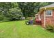 Home's spacious backyard with grassy area, outbuilding, trashcans, and steps up to red wooden deck at 143 Cedarwood Dr, Henderson, NC 27536