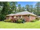 Wide shot of backyard features an all-brick home, red wooden deck, and bright green lawn and trees at 143 Cedarwood Dr, Henderson, NC 27536