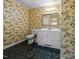 Cozy bathroom with floral wallpaper, single sink vanity, and decorative mirror at 143 Cedarwood Dr, Henderson, NC 27536