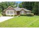 Charming one story brick home with bright green lawn and front entrance framed by small bushes and shrubs at 143 Cedarwood Dr, Henderson, NC 27536